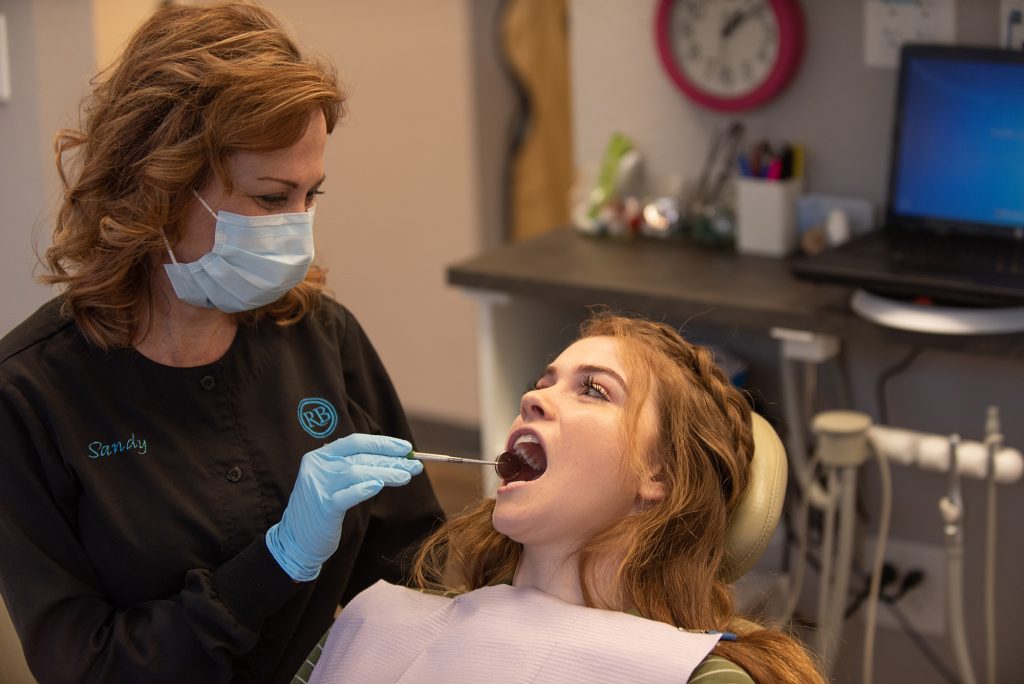 dental chair Dental hygienist wearing a mask examines a female patient in the dental chair during a checkup.